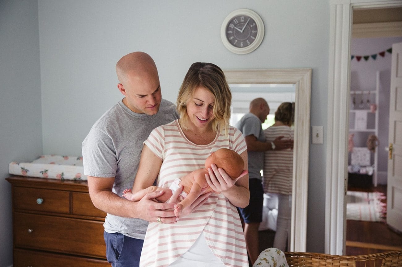A documentary photograph of new parents holding their newborn daughter during their lifestyle newborn session in Boston, Massachusetts