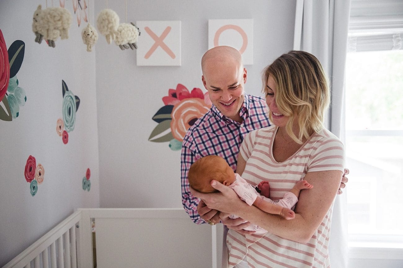 A documentary photograph of new parents smiling at their newborn daughter during their in home lifestyle session in Boston, Massachusetts