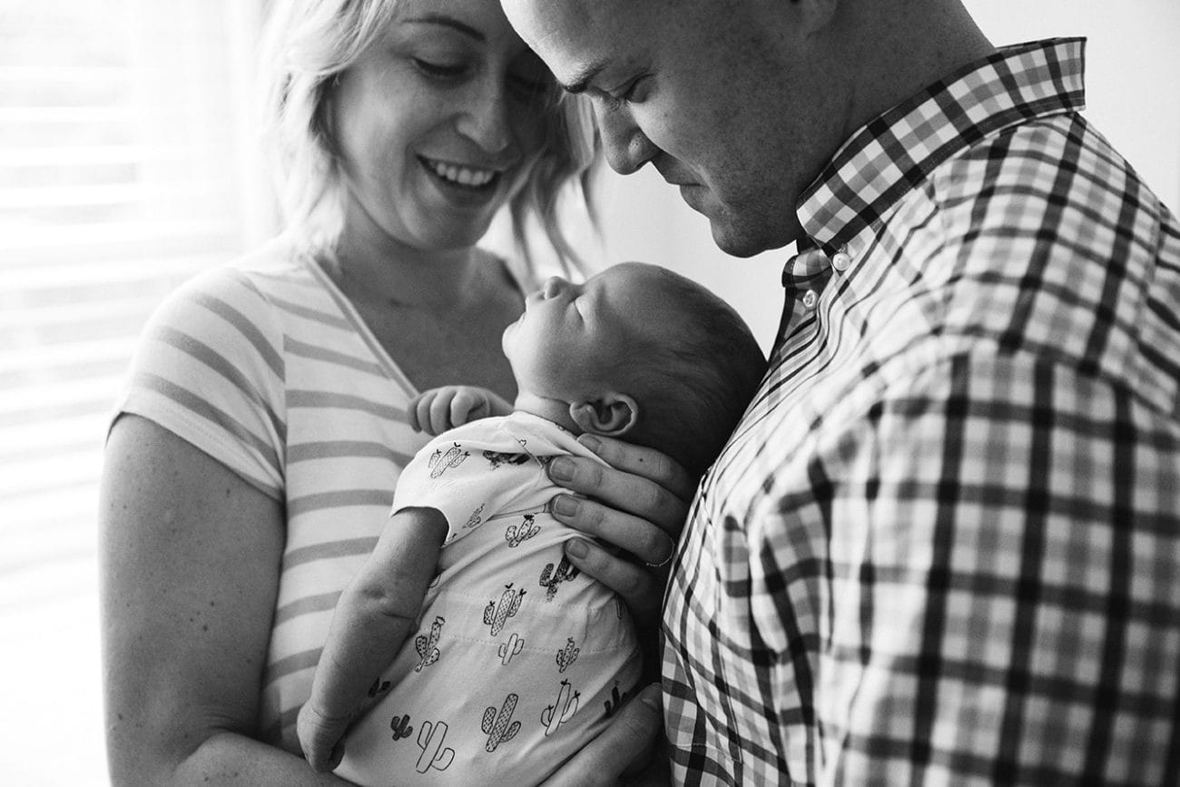 A documentary photograph of new parents admiring their newborn daughter during an in home lifestyle session in Boston, Massachusetts