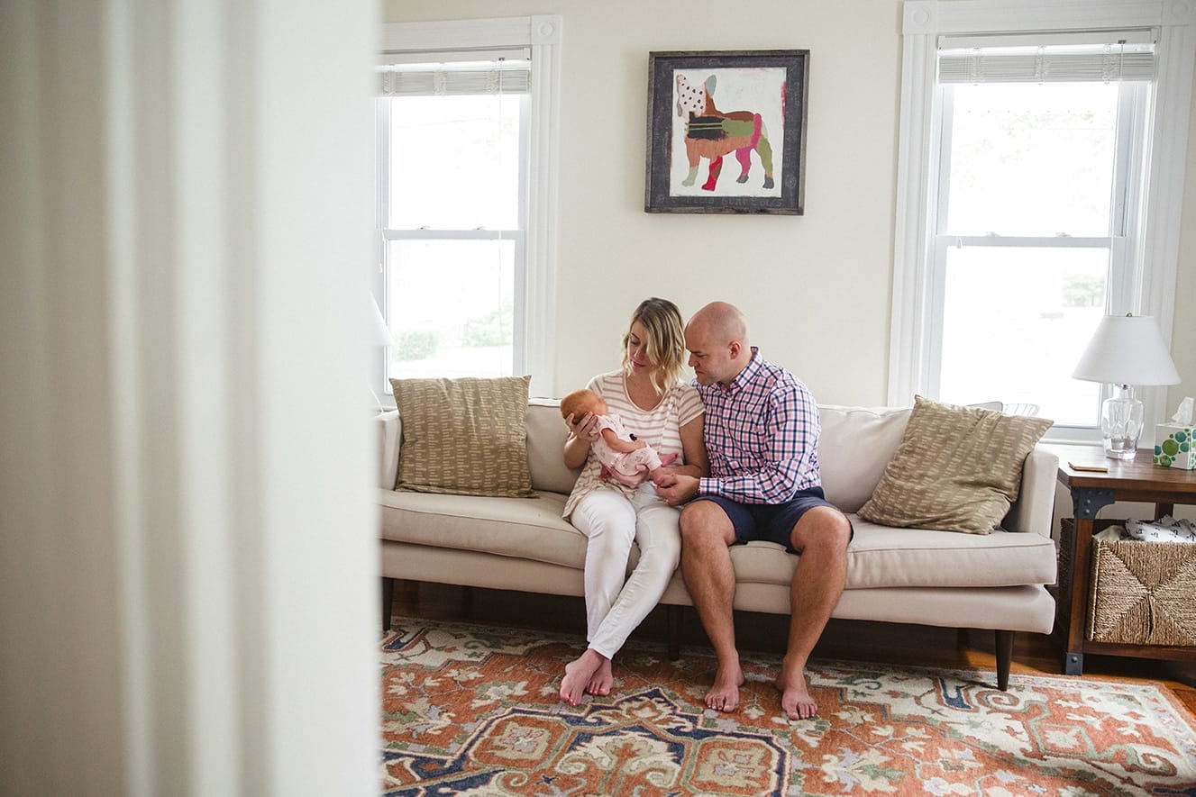 A documentary photograph of new parents holding their newborn daughter during an in home lifestyle session in Boston, Massachusetts