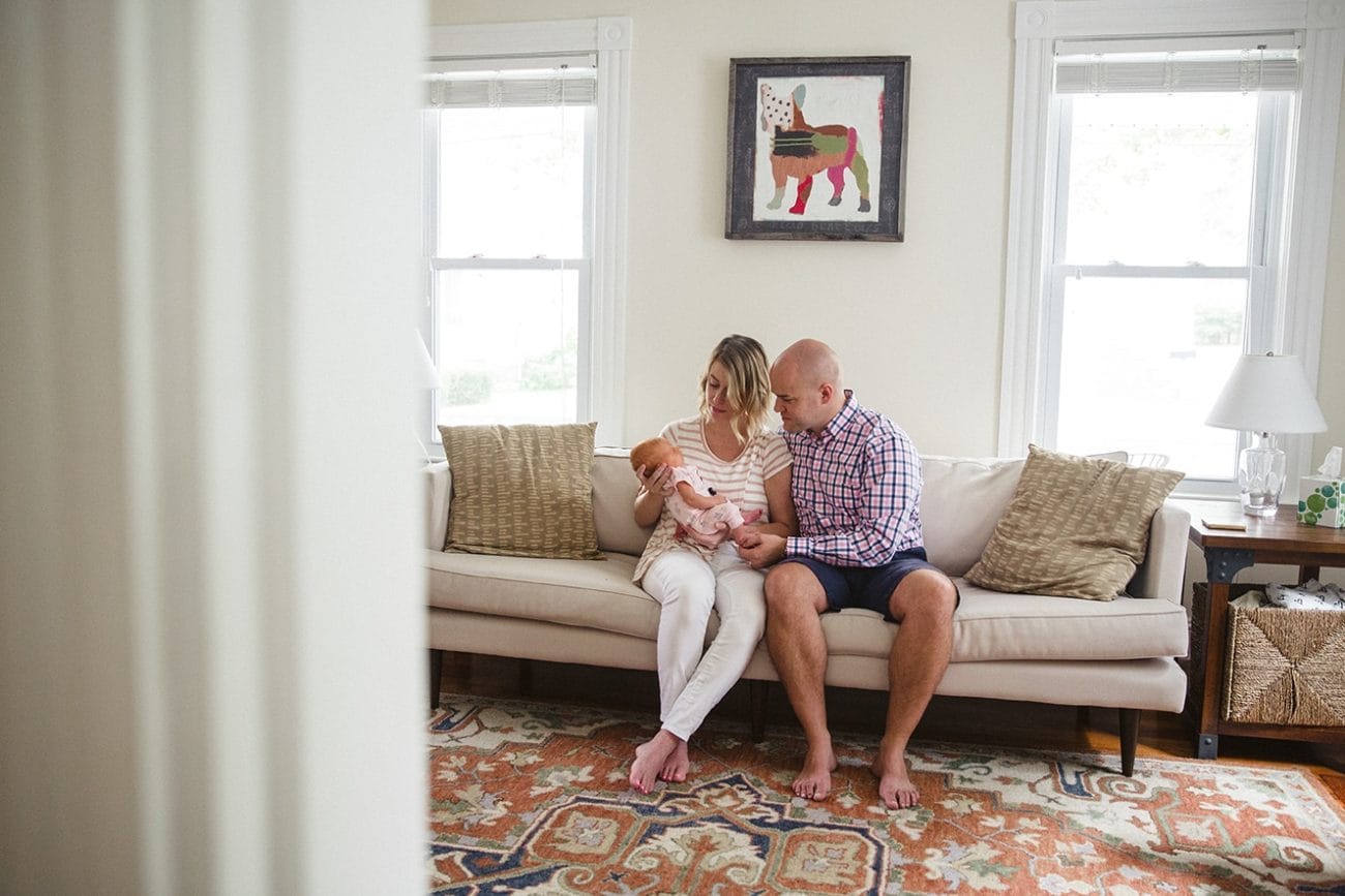 A documentary photograph of new parents holding their newborn daughter during an in home lifestyle session in Boston, Massachusetts