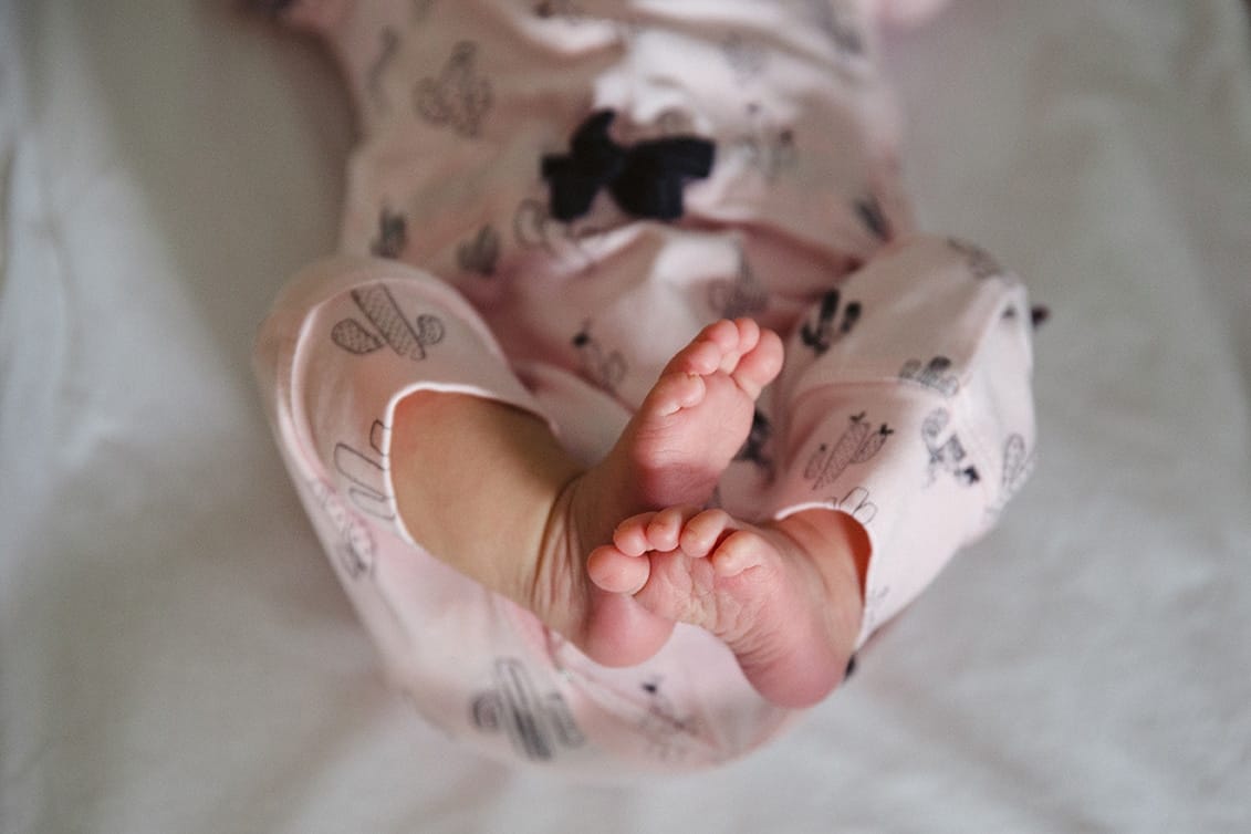 A documentary photograph of a newborns feet as she settles in her bassinet during an in home lifestyle session in Boston, Massachusetts