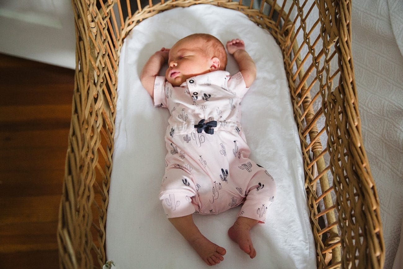 A documentary photograph of a newborn baby sleeping in her bassinet during an in home lifestyle session in Boston, Massachusetts