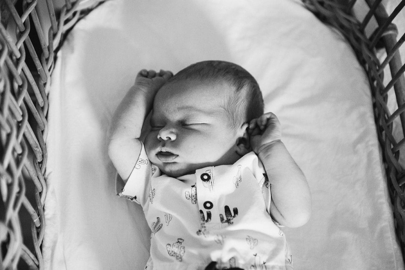 A documentary photograph of newborn sleeping in her bassinet during an in home lifestyle session in Boston, Massachusetts