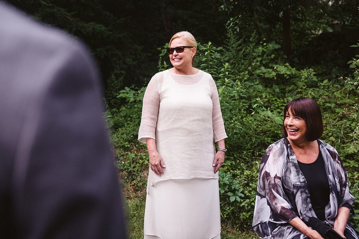 A documentary photograph of the bride's mother and grandmother laughing before a plimoth plantation wedding in plymouth, massachusetts