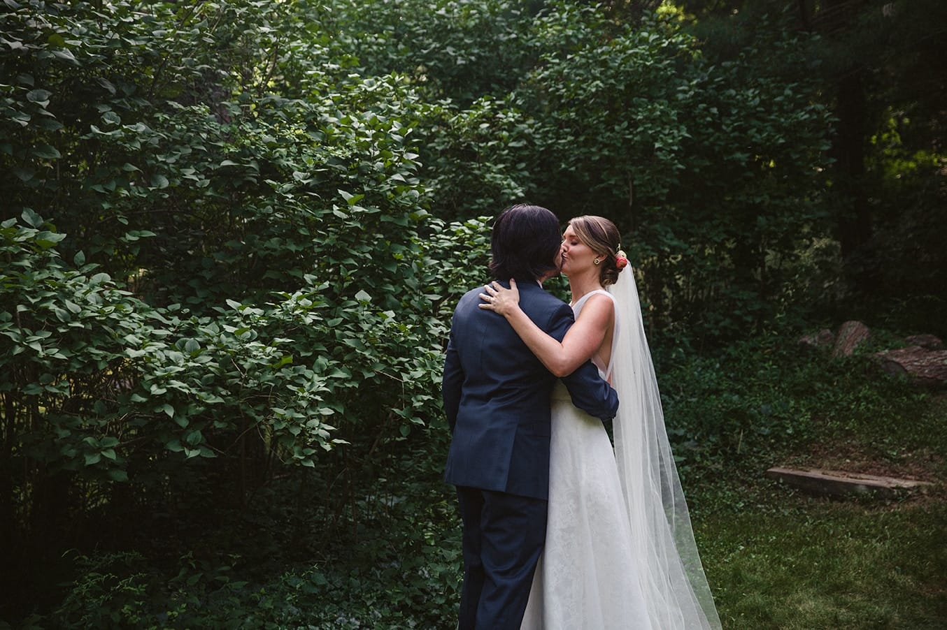 A documentary photograph of a bride and groom sharing a private kiss moments after they walk down the aisle as husband and wife during their plimoth plantation wedding in plymouth, massachusetts