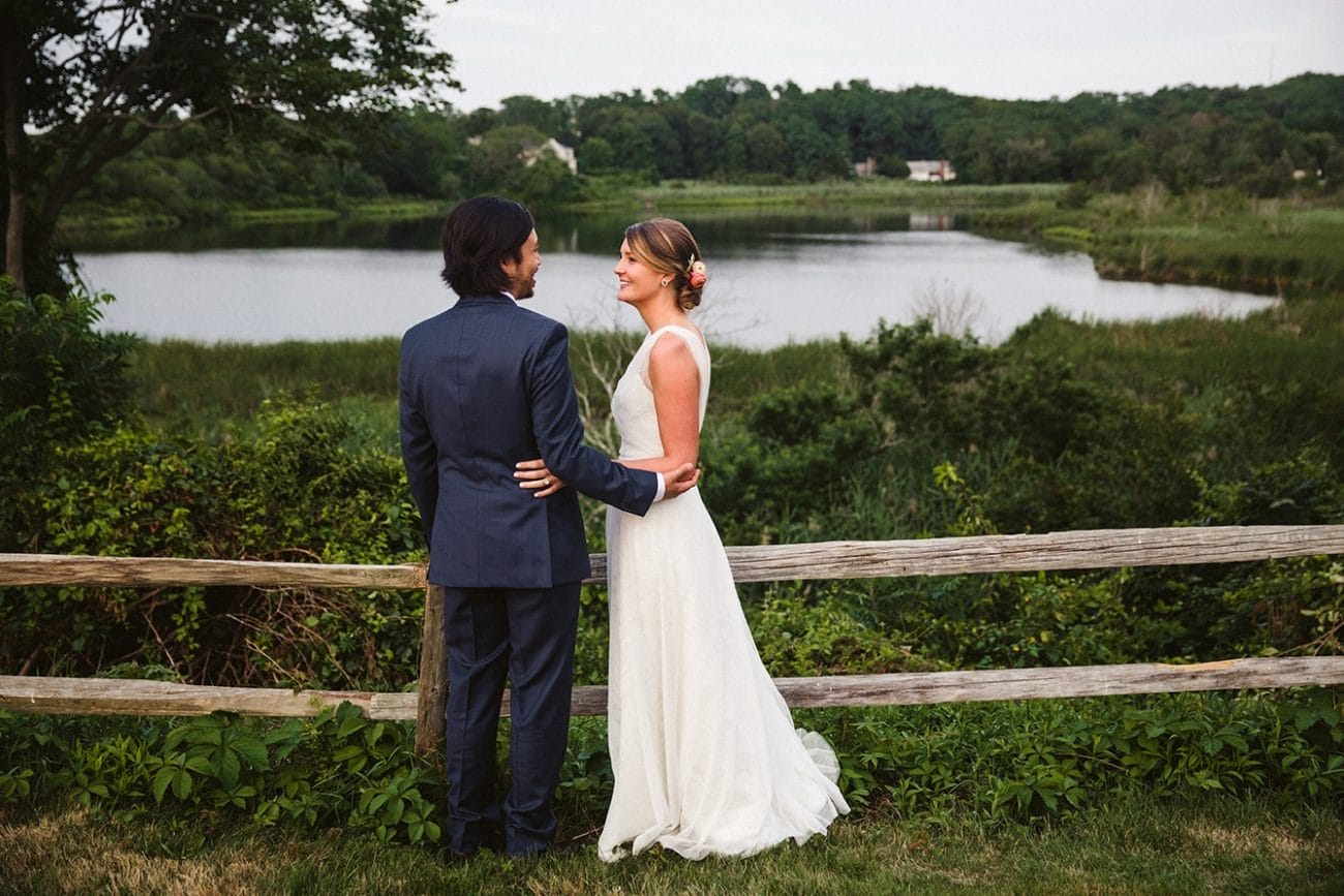 A portrait of a bride and groom talking by the water during their plimoth plantation wedding in plymouth, massachusetts