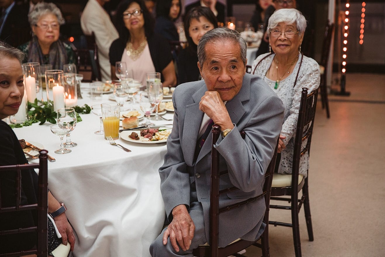 A documentary photograph of a grandfather watching the toasts at a plimoth plantation wedding in plymouth, massachusetts