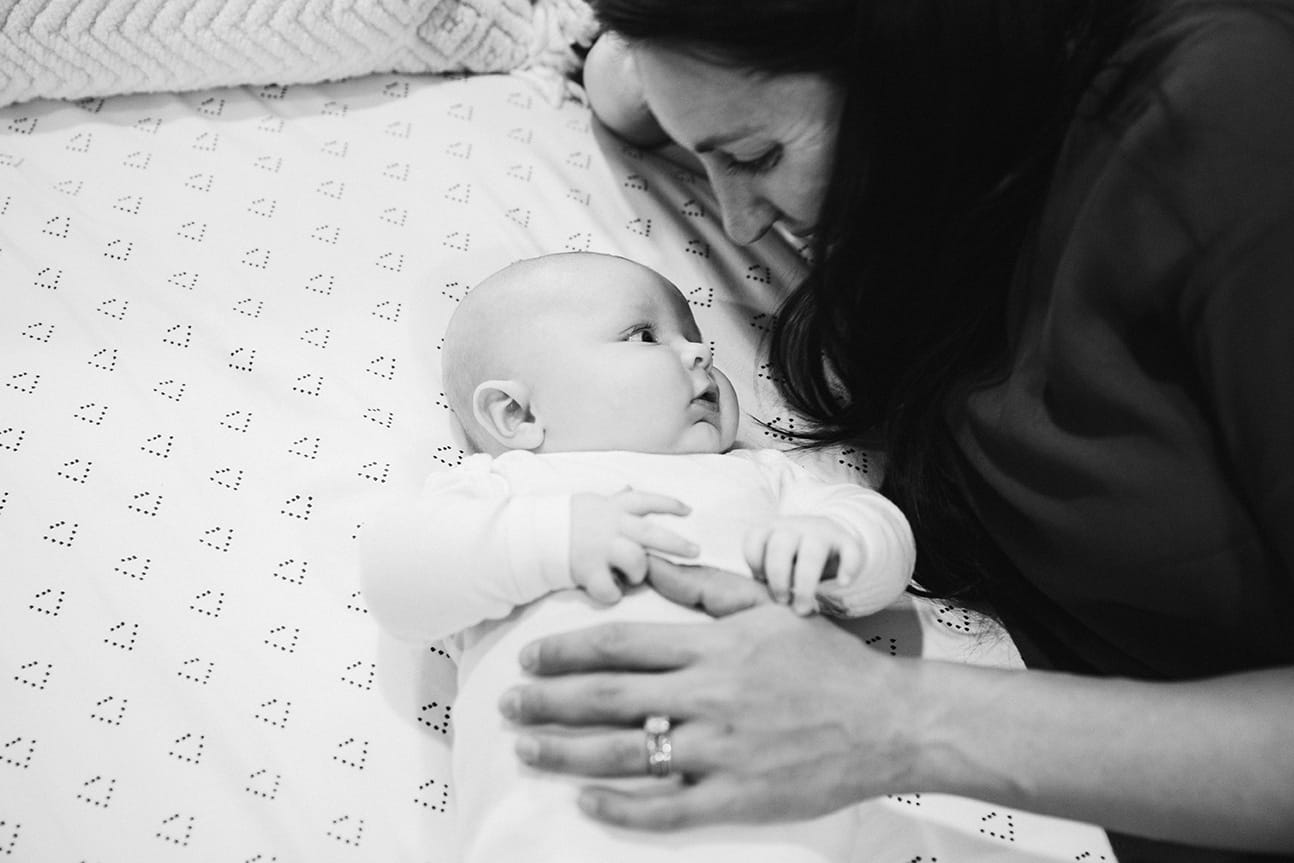 A documentary photograph of a mom cuddling with her baby boy during an in home family lifestyle session in Boston, Massachusetts