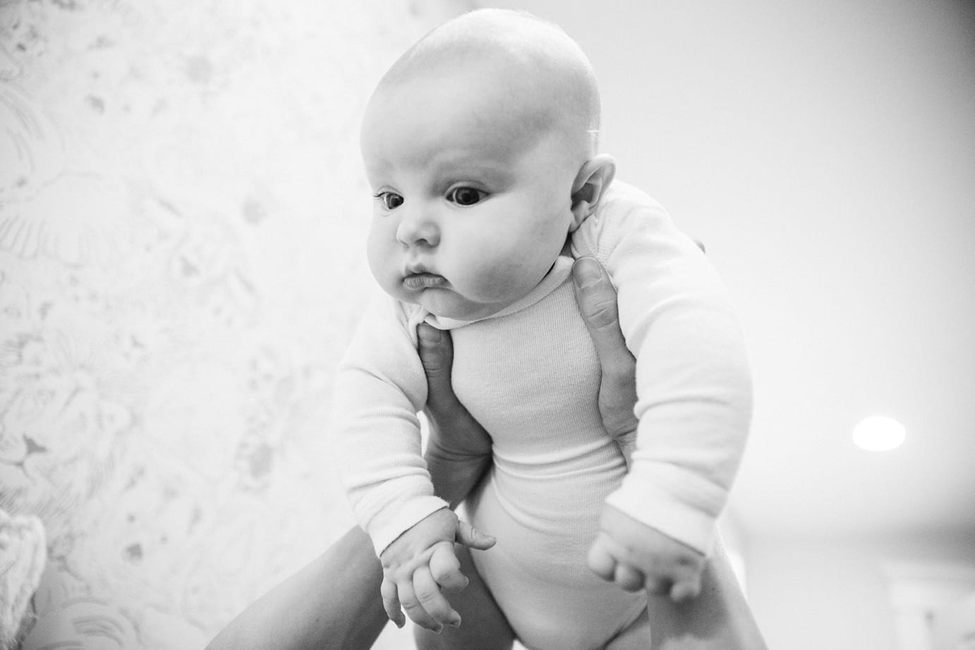 A documentary photograph of a baby boy looking at his mom while they play during an in home family lifestyle session in Boston, Massachusetts