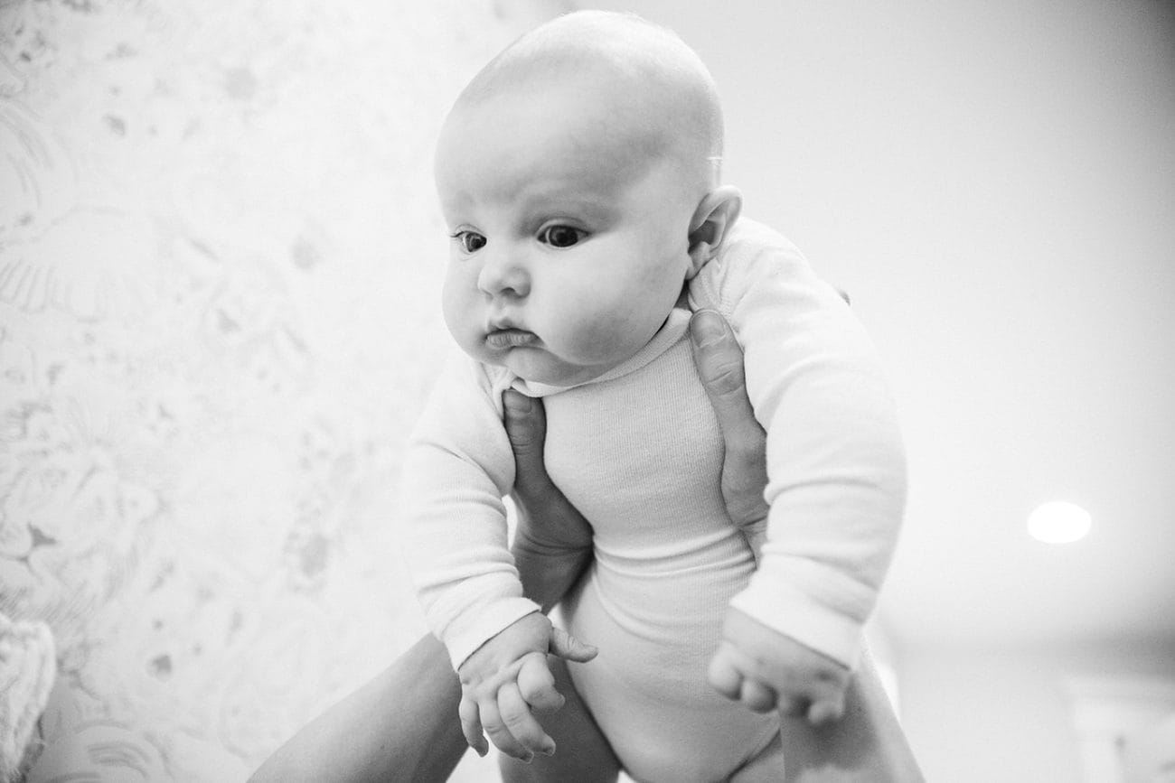 A documentary photograph of a baby boy looking at his mom while they play during an in home family lifestyle session in Boston, Massachusetts