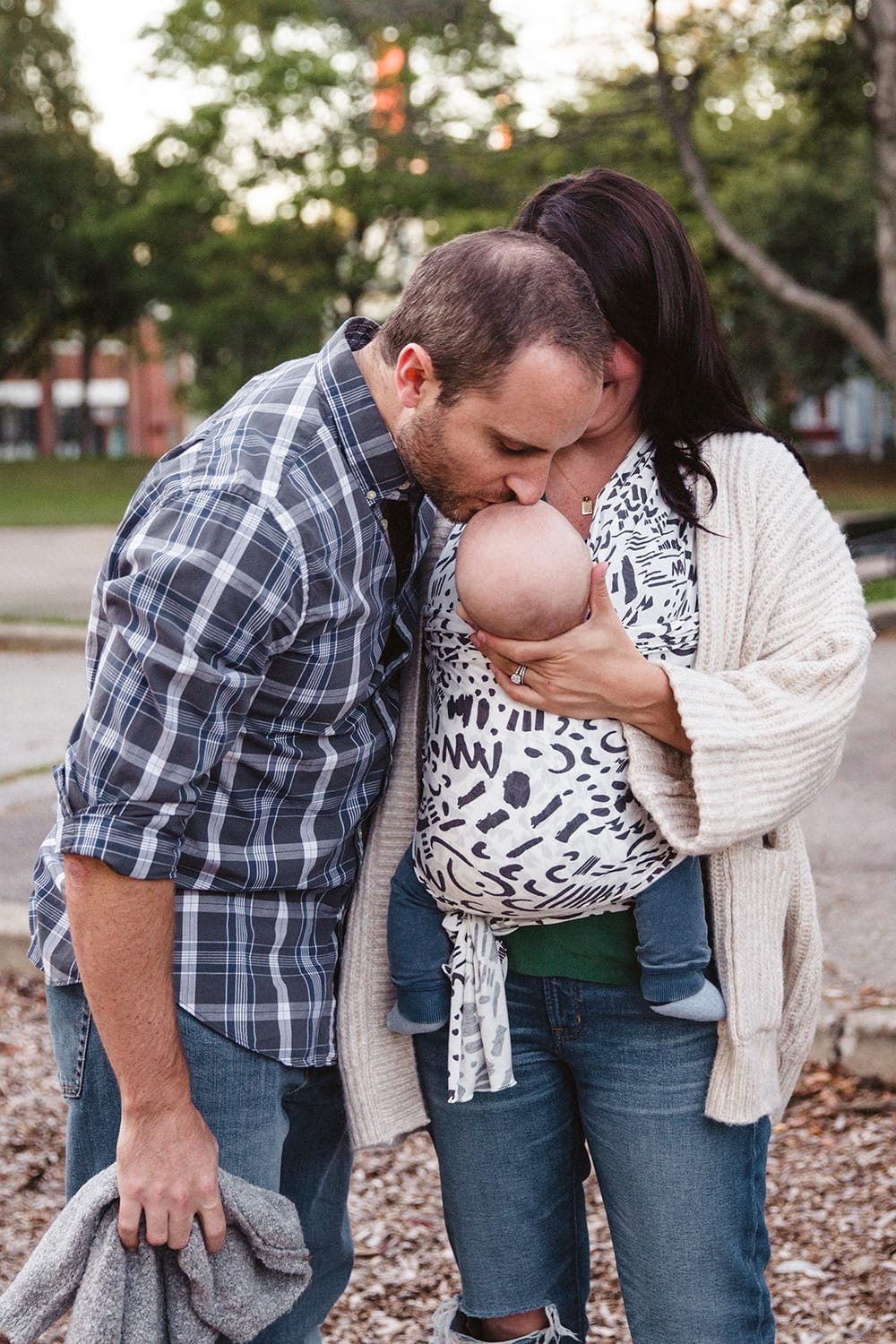 A documentary photograph of a father kissing his baby boy during a family lifestyle session in Boston, Massachusetts