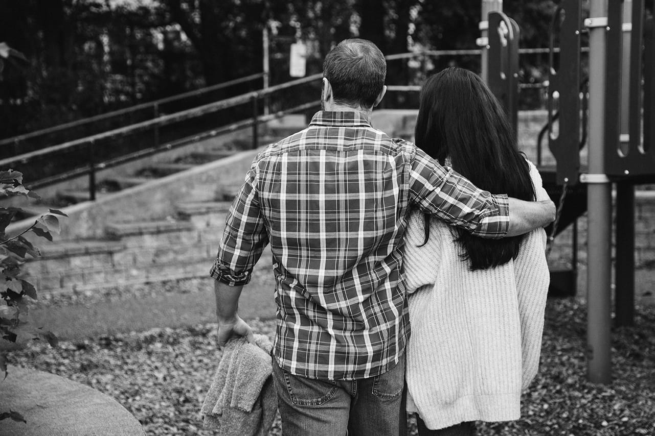A documentary photograph of mom and dad walking with their arms around each other during a family lifestyle session in Boston, Massachusetts