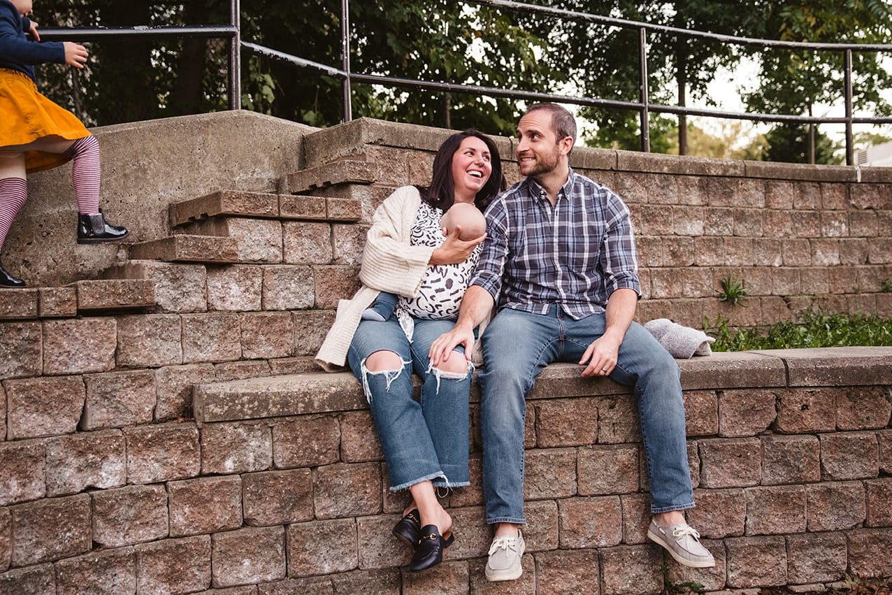 A documentary photograph of a family laughing at the playground during a family lifestyle session in Boston, Massachusetts