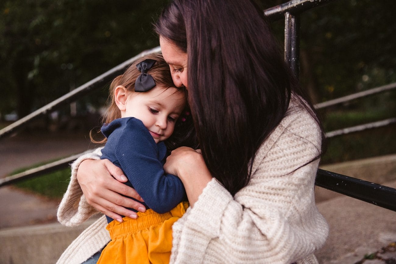 A documentary photograph of a mom hugging her daughter at the playground during a family lifestyle session in Boston, Massachusetts