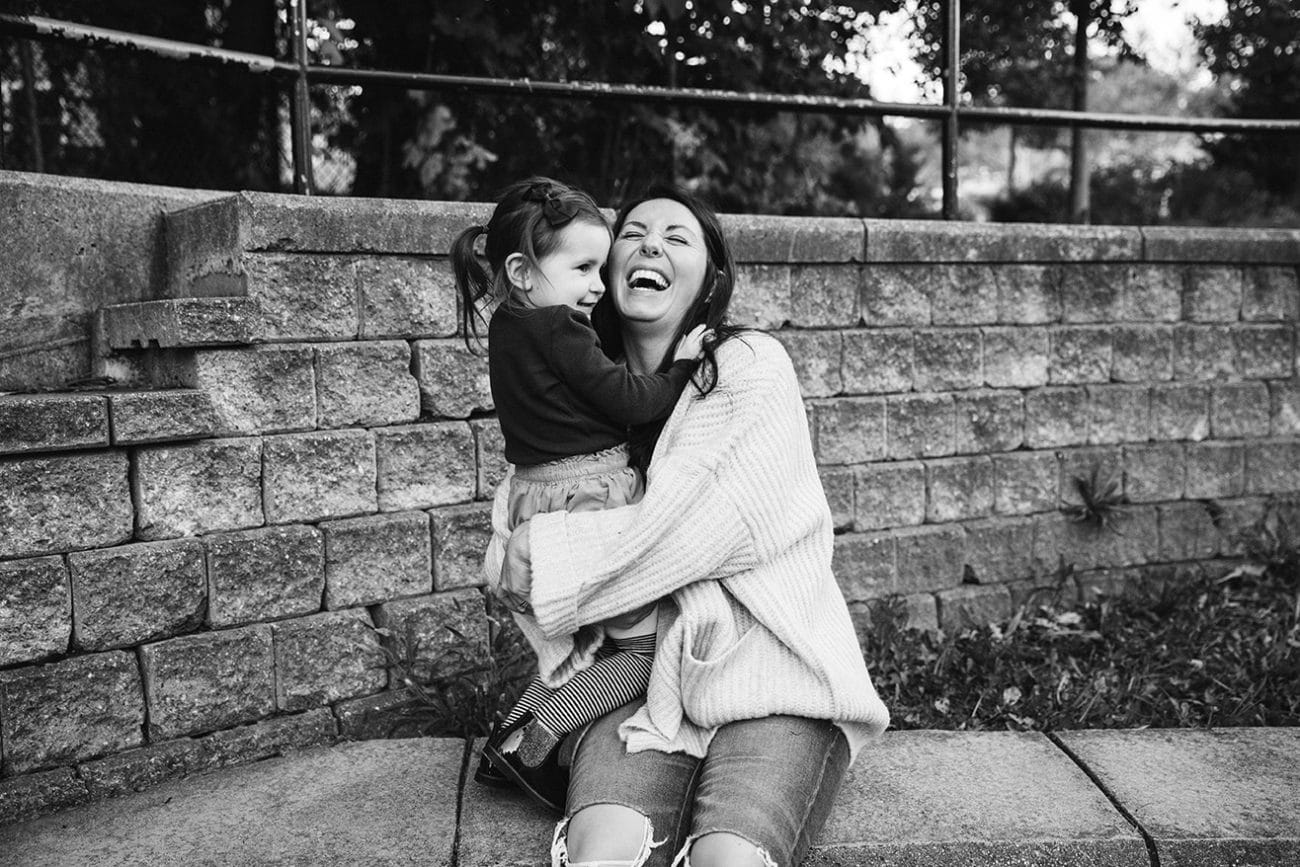 A documentary photograph of a mom and daughter laughing at the playground during a family lifestyle session in Boston, Massachusetts