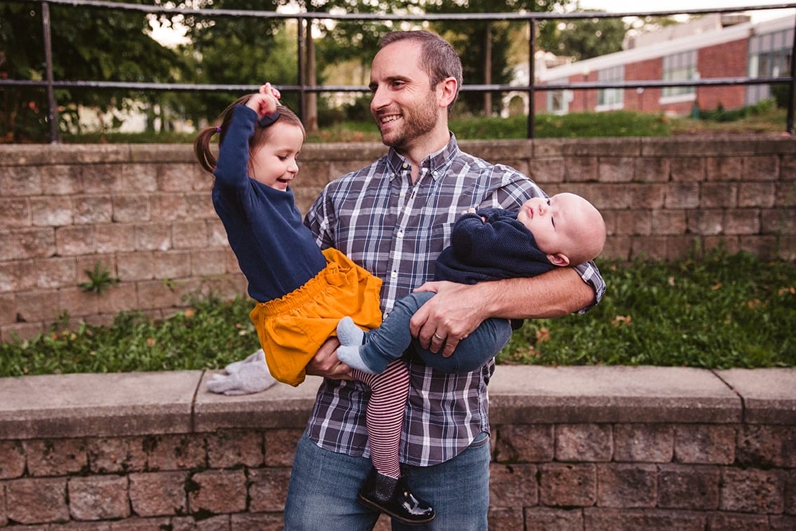 A documentary photograph of a father holding his son and daughter during a family lifestyle session in Boston, Massachusetts