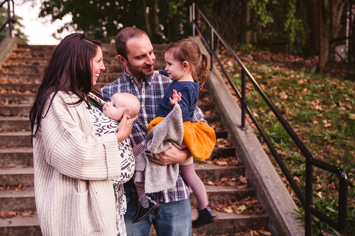A documentary photograph of a family laughing together as they leave the playground during a family lifestyle session in Boston, Massachusetts