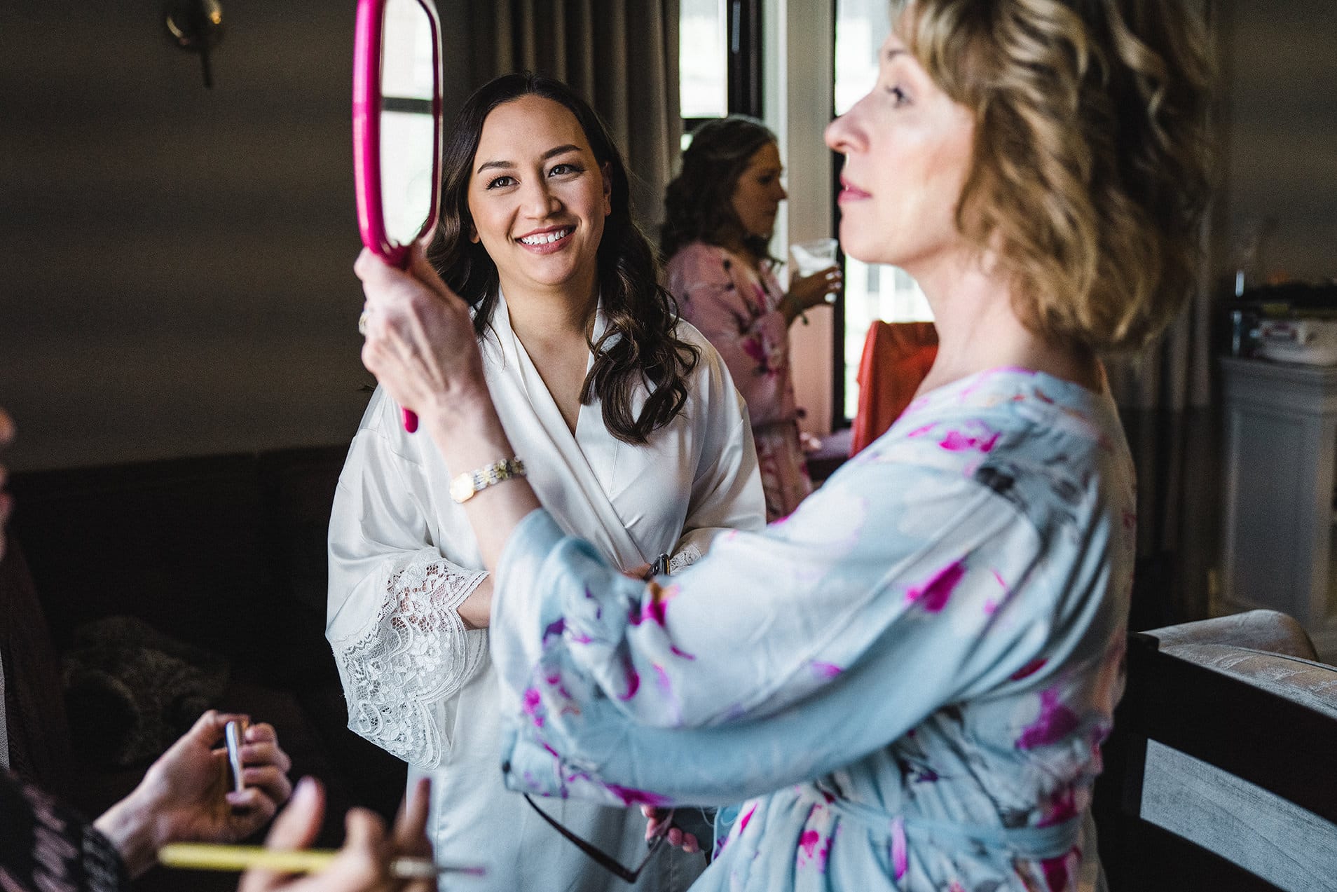 A documentary photograph of the bride watching her mom look in the mirror before her Fairmont Copley Wedding in Boston