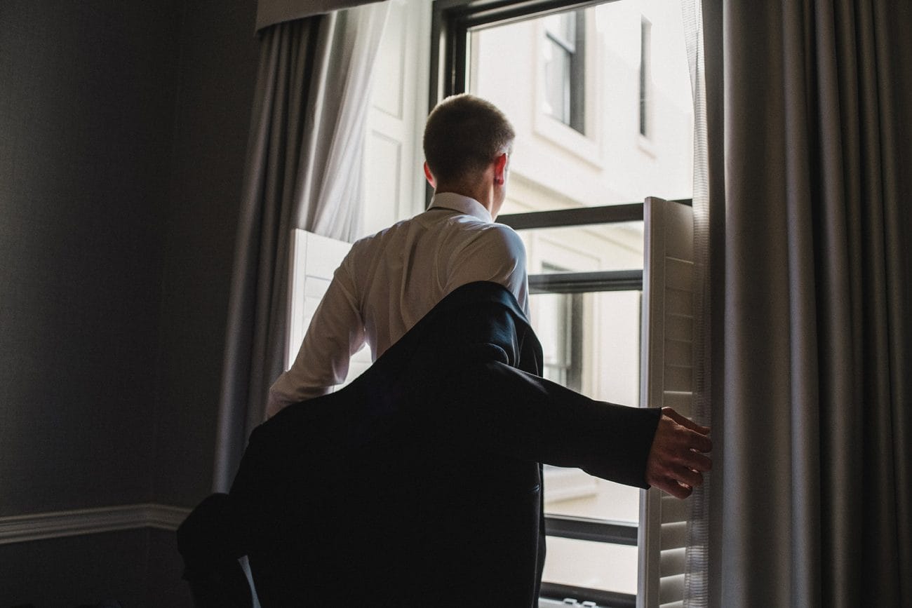 A documentary photograph of a groom putting on his jacket before a Fairmont Copley Wedding in Boston