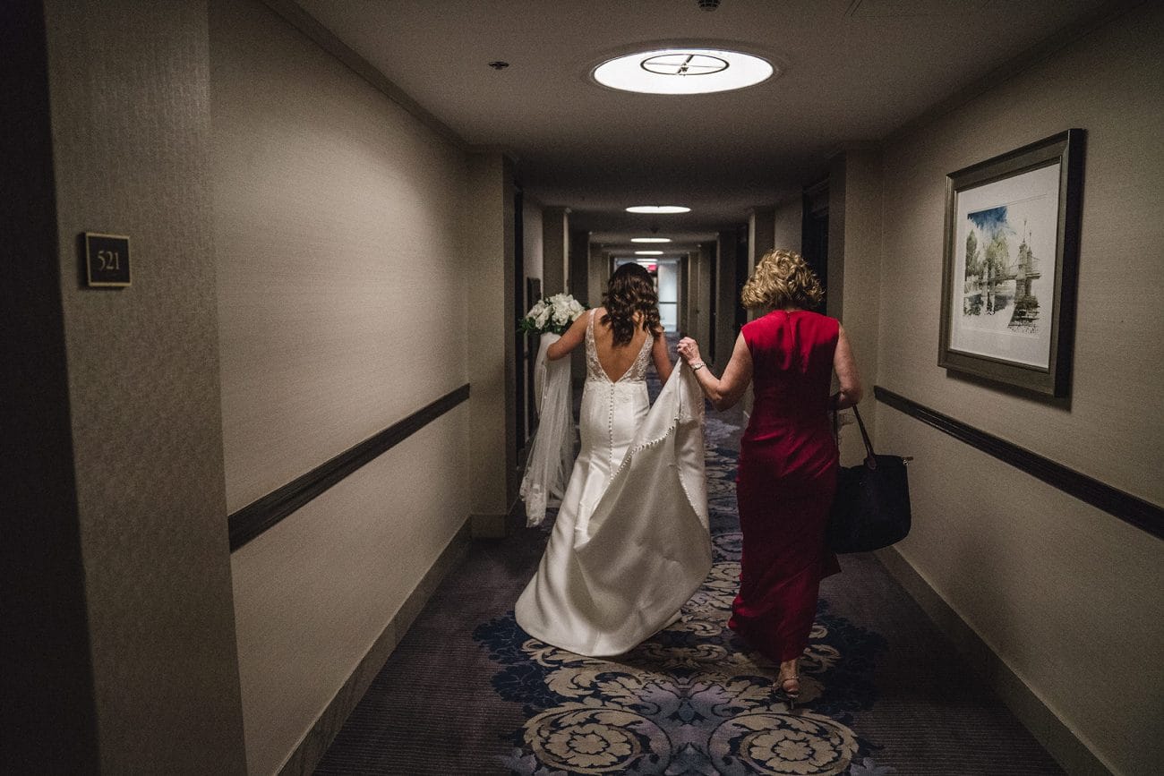 A documentary photograph of the bride and her mom walking down the hallway before her Fairmont Copley Wedding in Boston