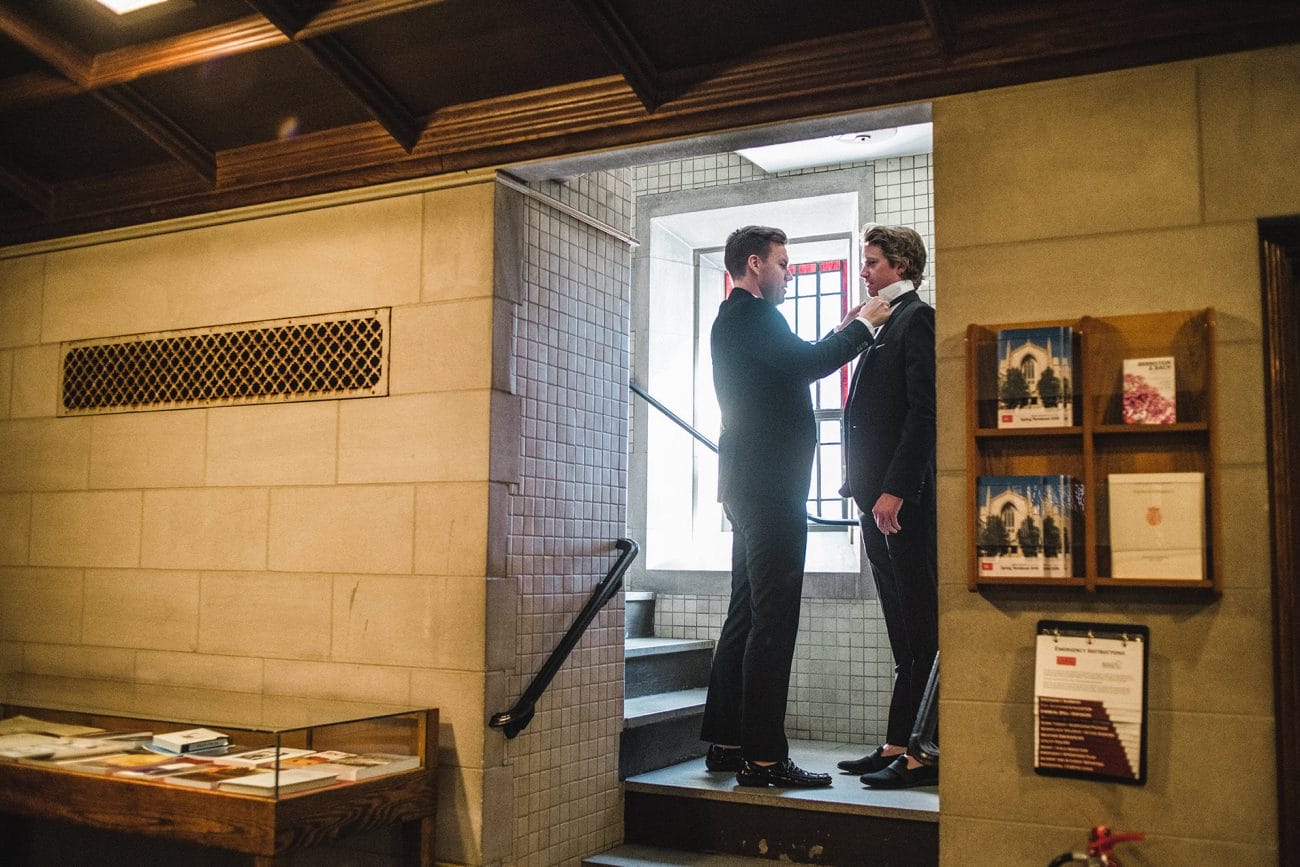 A documentary photograph of guest putting on their ties before a Boston Wedding Ceremony at Marsh Chapel