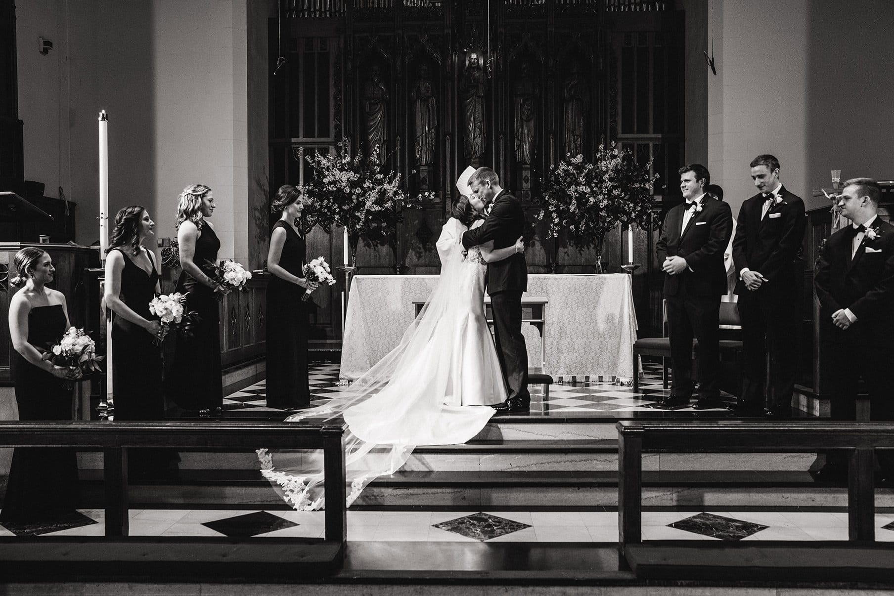 A documentary photograph of a bride and groom kissing during their Boston Wedding ceremony at Marsh Chapel