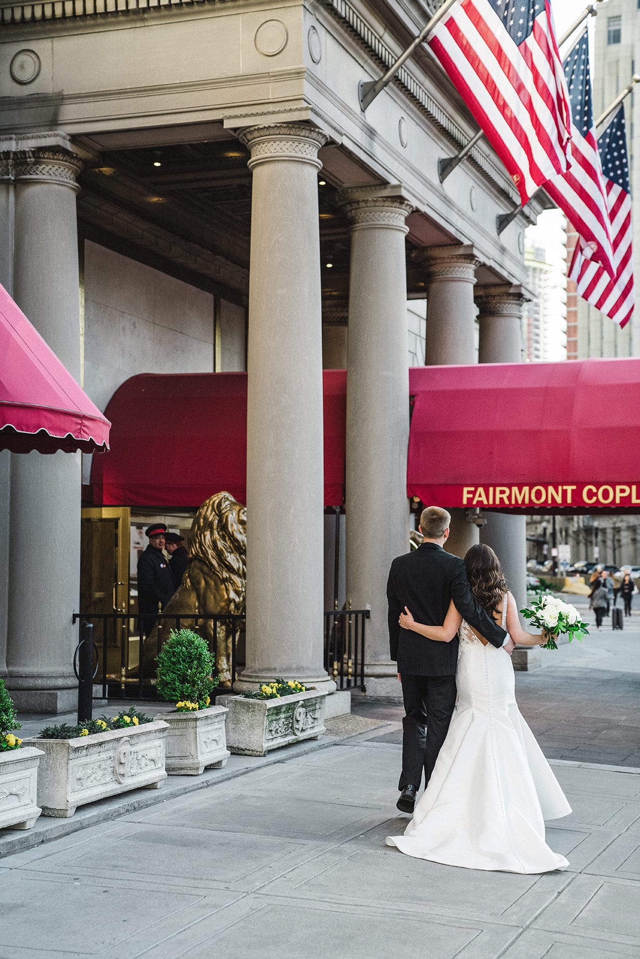 A candid portrait of a bride and groom walking into fairmont copley for their wedding reception