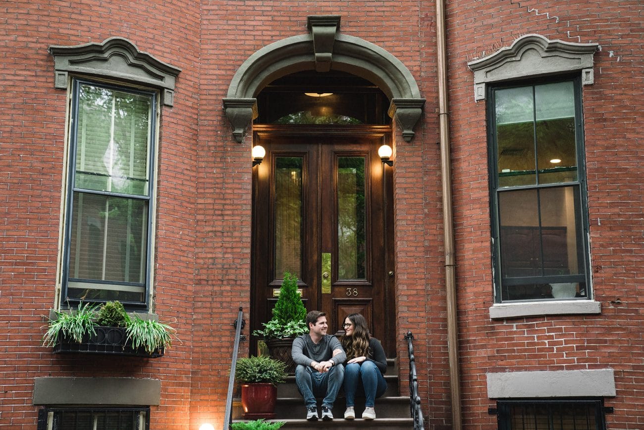 A couple sit on the steps of their home during an south end boston engagement session