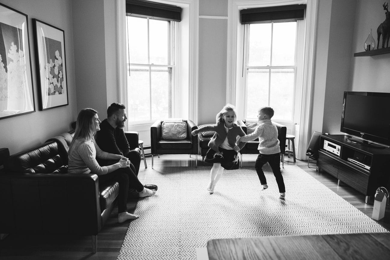 A family dances in the living room during their in home family session in the south end of Boston