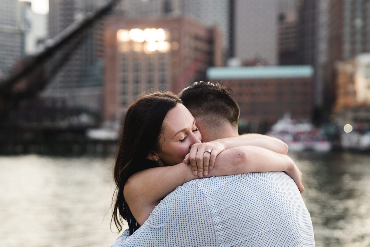 A documentary photograph of couple hugging during their fan pier engagement session in Boston's seaport district