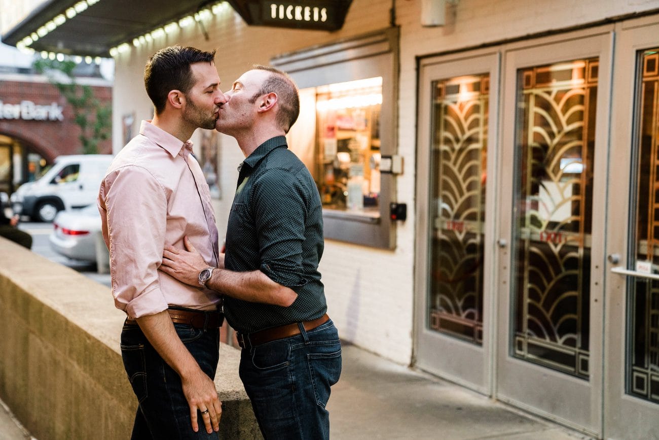 A documentary photograph of a couple kissing outside a movie theater during their Boston Engagement session