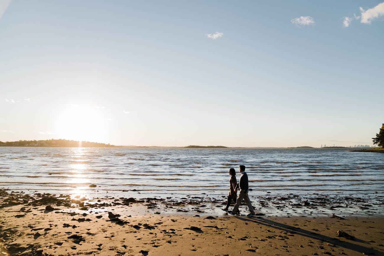 A documentary portrait of a couple walking on the beach during their boston engagement session at the world's end