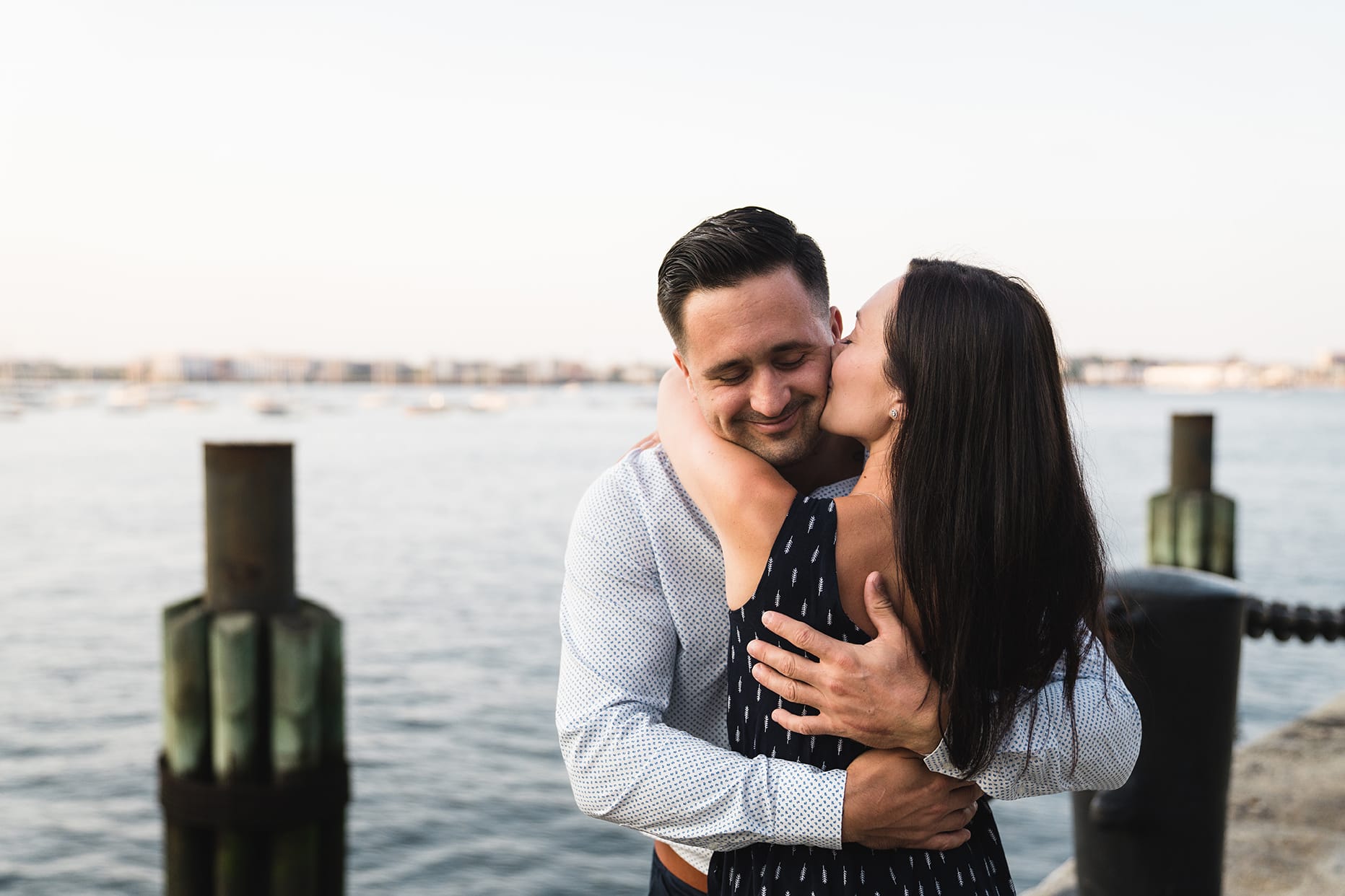 A documentary photograph of a couple hugging during their fan pier engagement session at Boston's seaport