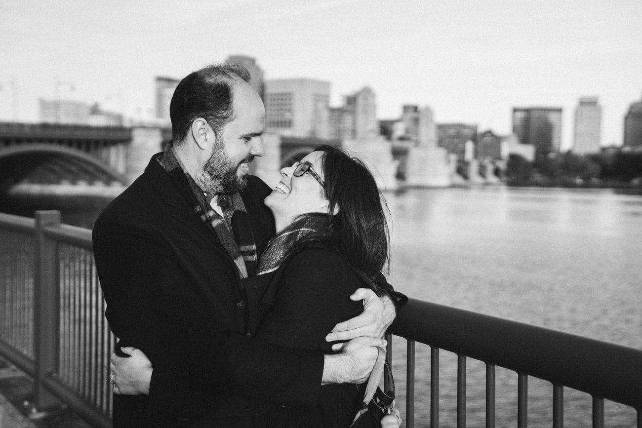 A documentary portrait of a couple laughing together on the Charles river esplanade during their boston engagement session