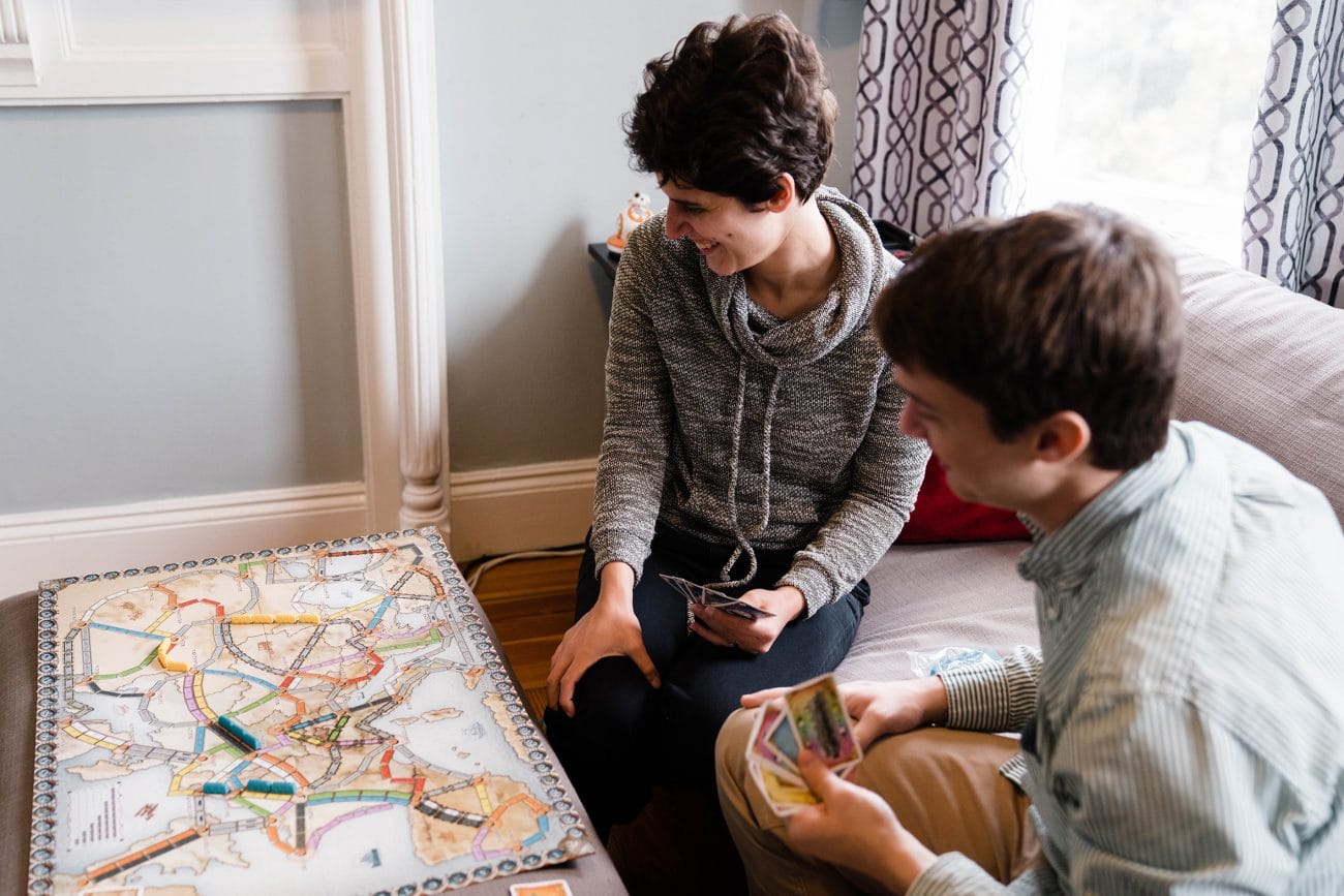 A documentary photograph of a couple playing a board game together during their in home boston engagement session