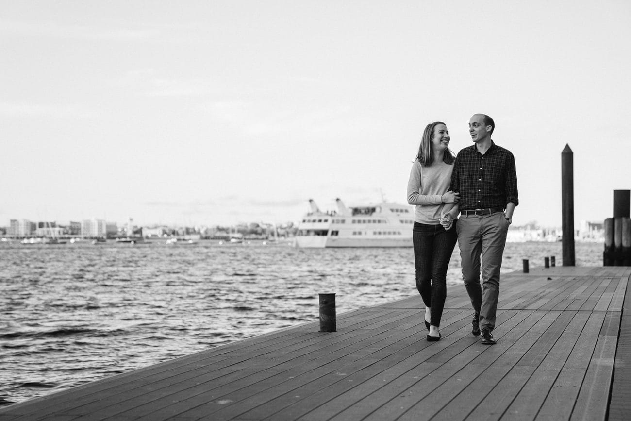 A documentary photograph of a couple walking on fan pier during their Boston engagement session