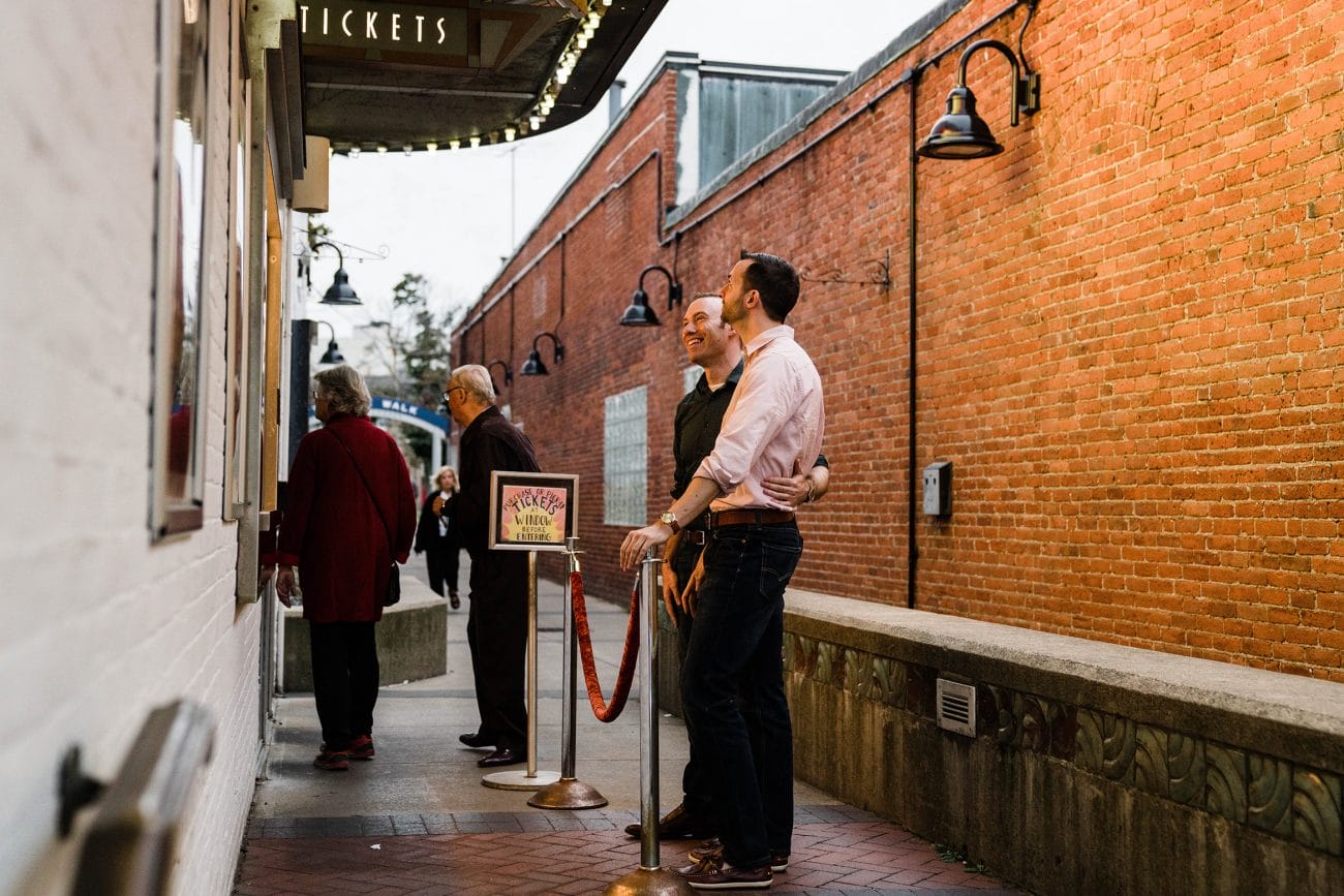 A documentary photograph of a couple waiting for movie tickets during their Boston engagement session