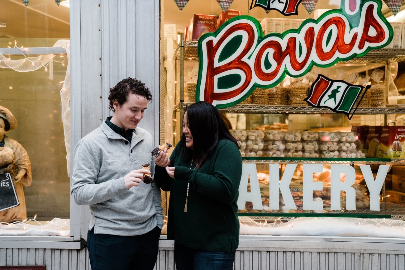 A documentary photograph of couple enjoying a cannoli at Bova's during their Boston north end engagement session