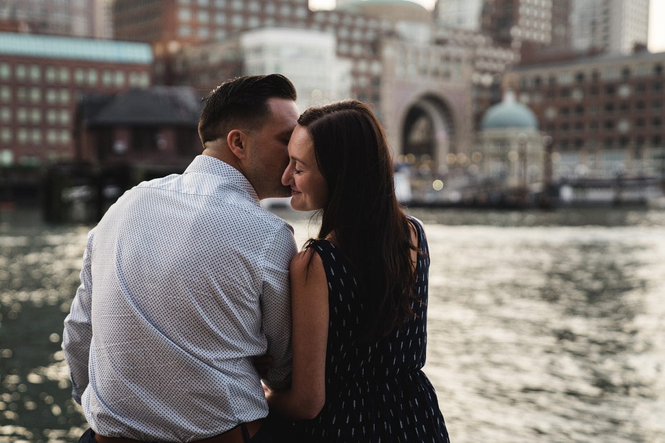 A documentary portrait of a couple snuggling their Boston seaport engagement session at Fan Pier