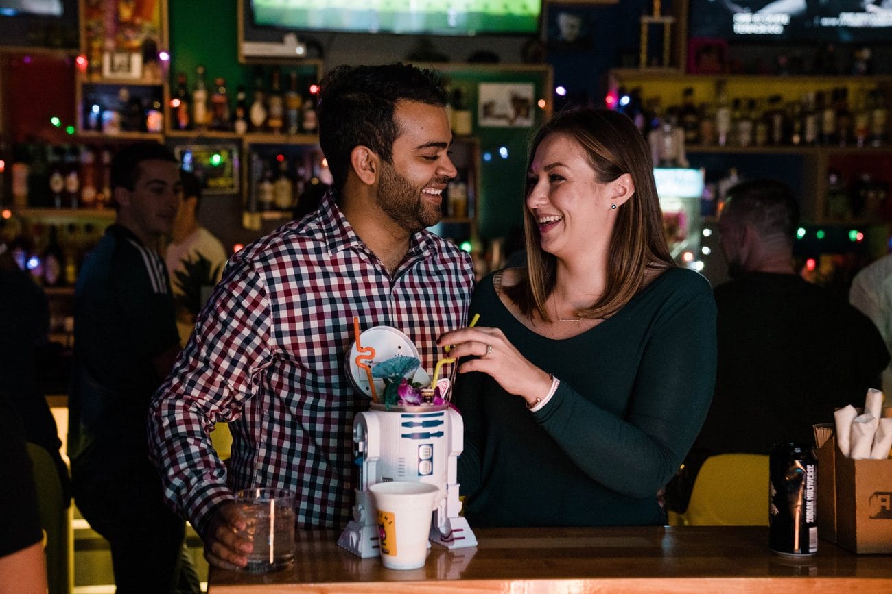 A documentary photograph of a couple having a drink at Roxy's Arcade during a Boston Engagement session