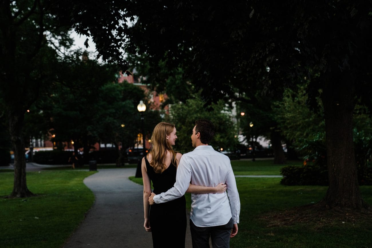 A documentary photograph of a couple walking through the Boston public gardens during their Boston engagement session