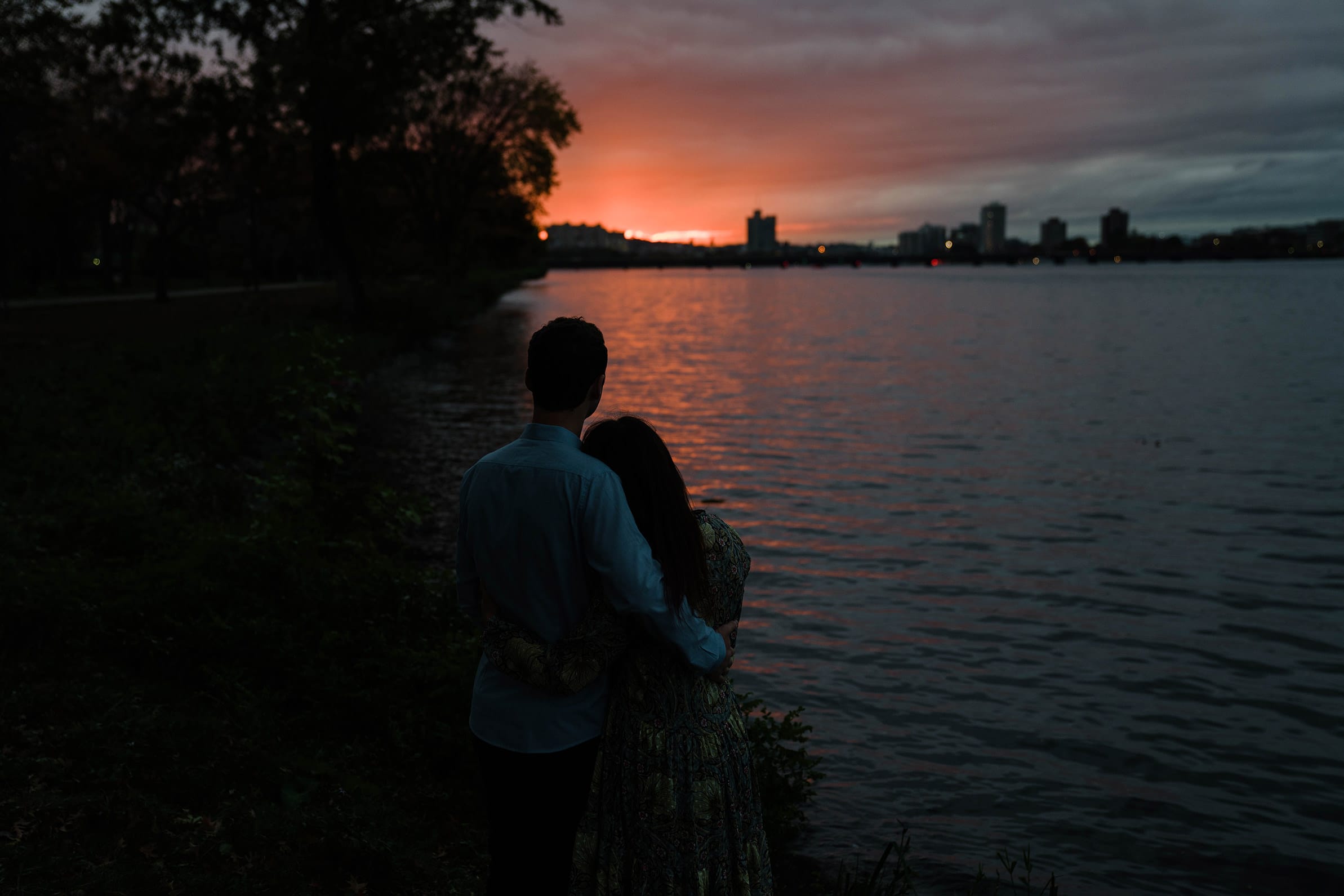 A documentary photograph of a couple enjoying the sunset on the Charles River Esplanade during their Boston engagement session