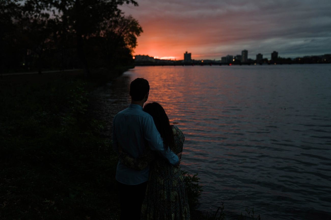 A documentary photograph of a couple enjoying the sunset on the Charles River Esplanade during their Boston engagement session