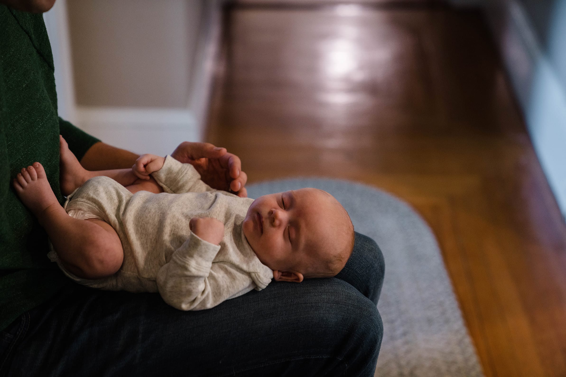 A best of boston family photograph of a newborn baby sleeping in his father's lap during an in home family session in Boston