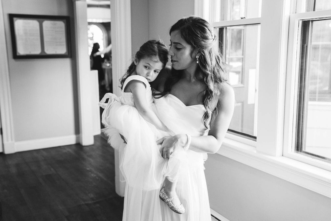 A best of Boston wedding reception photograph of a bride holding a sleepy flower girl during her reception at the Inn at Hastings Park