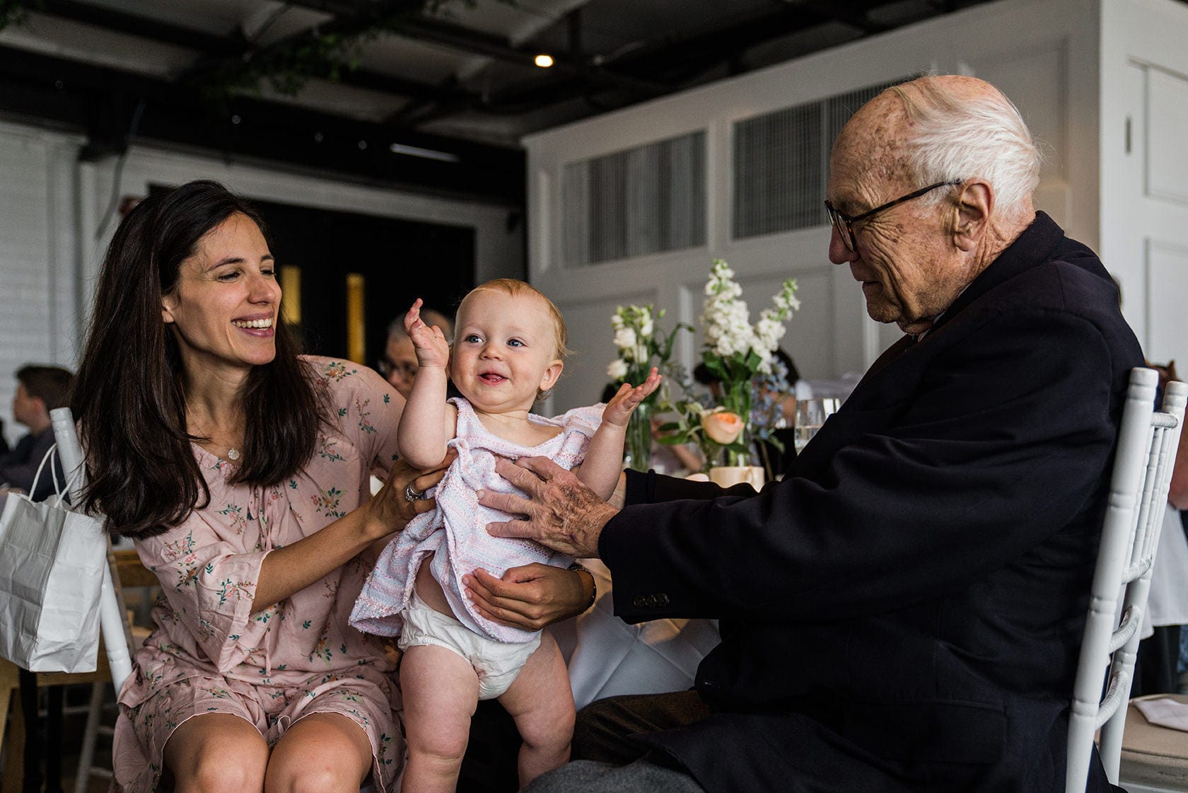 A best of Boston wedding photograph of a baby playing with her mom and grandfather during a Taj Boston rooftop wedding