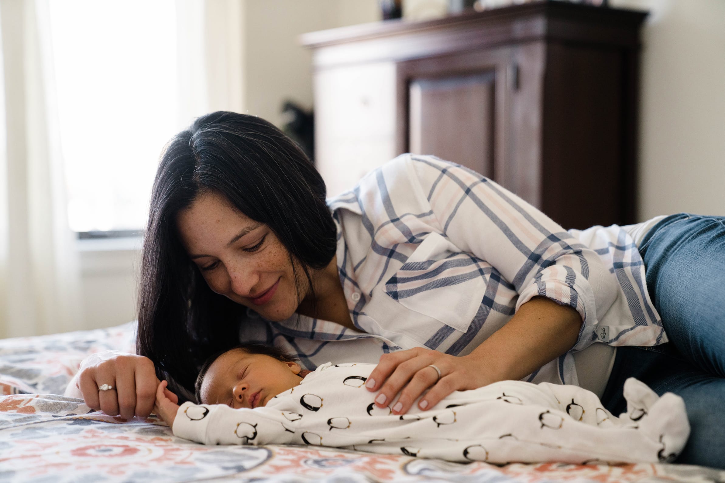 A best of Boston family photograph of a mom cuddling her newborn son as he sleeps during a in home lifestyle newborn session