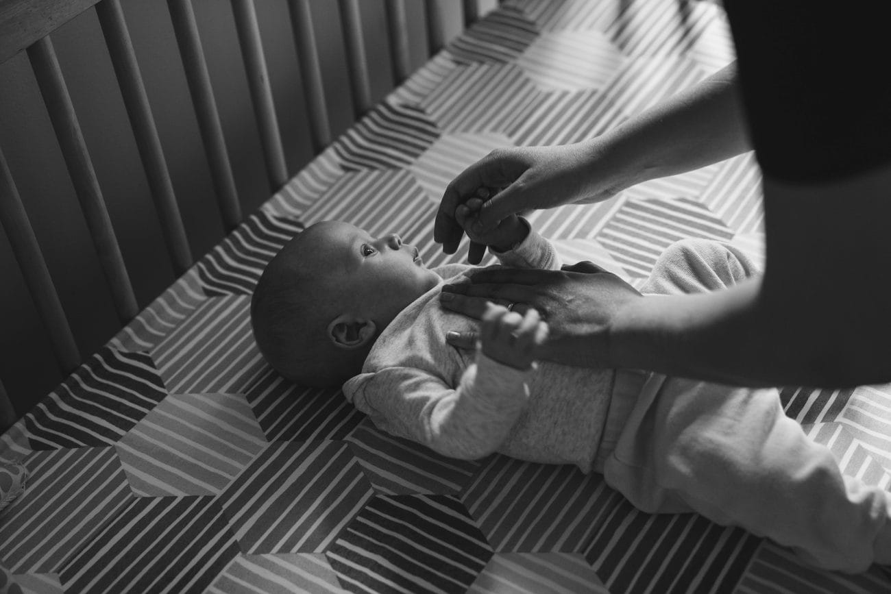 A best of Boston family photograph of mom helping her baby into the crib during an in home family session in Boston