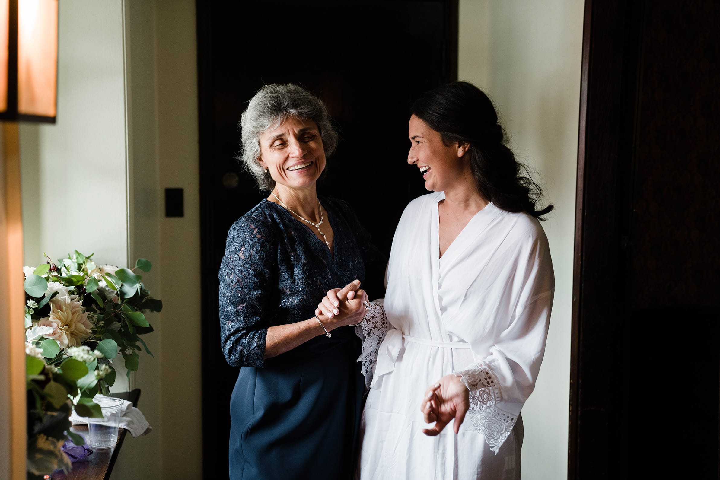 A best of Boston wedding photograph of bride and mother of the groom of talking and laughing before her willowdale estate wedding